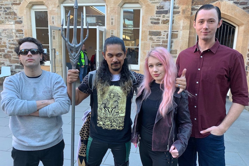One person with a trident and yellow eyes with three other people