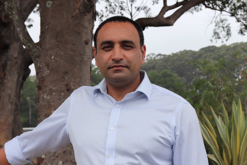 A man in a business shirt looks at the camera