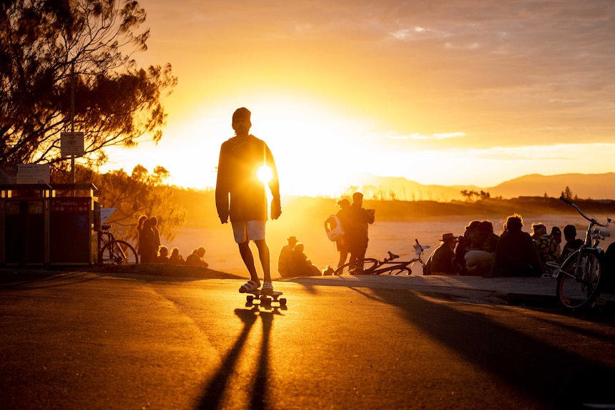 A man skates as the sun sets behind him in Byron Bay.