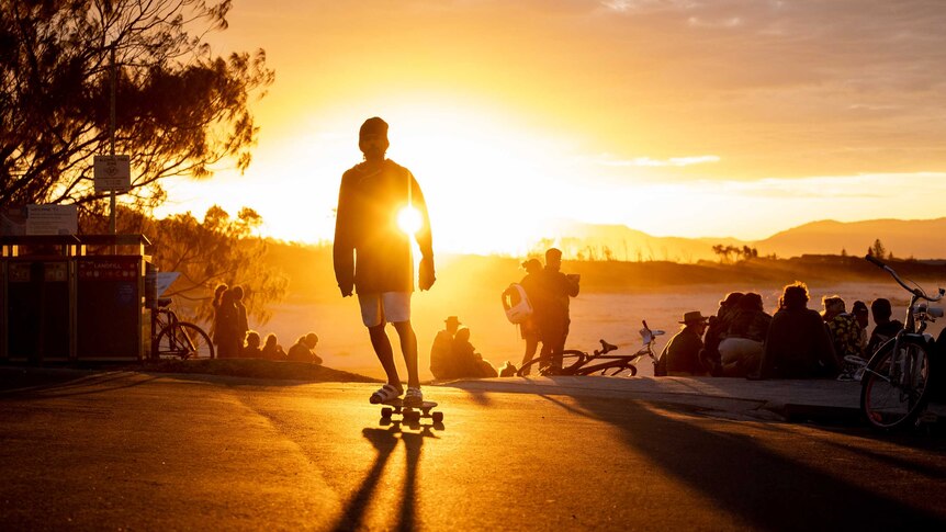 A man skates as the sun sets behind him in Byron Bay.