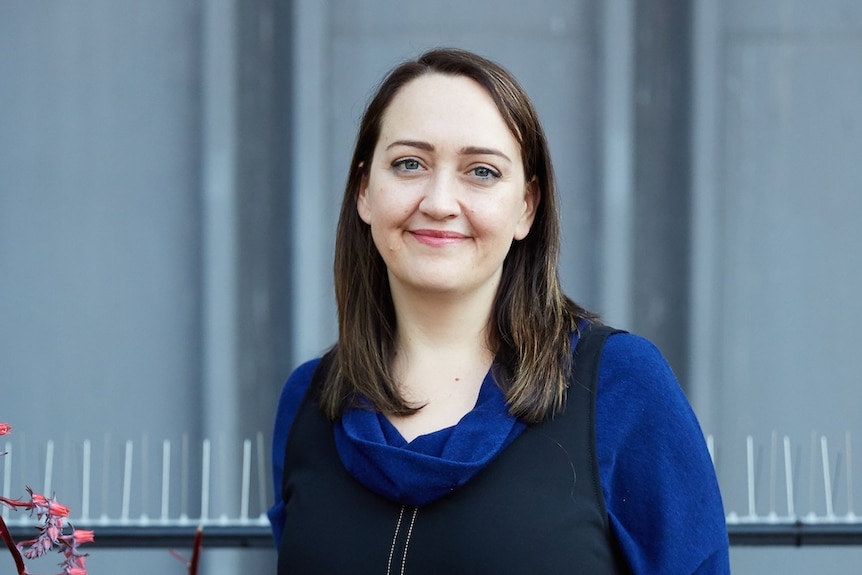 Colour photograph of Emily Maguire standing on top of a city rooftop.