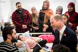 Prince William talks to a man next to a hospital bed with a small girl in it