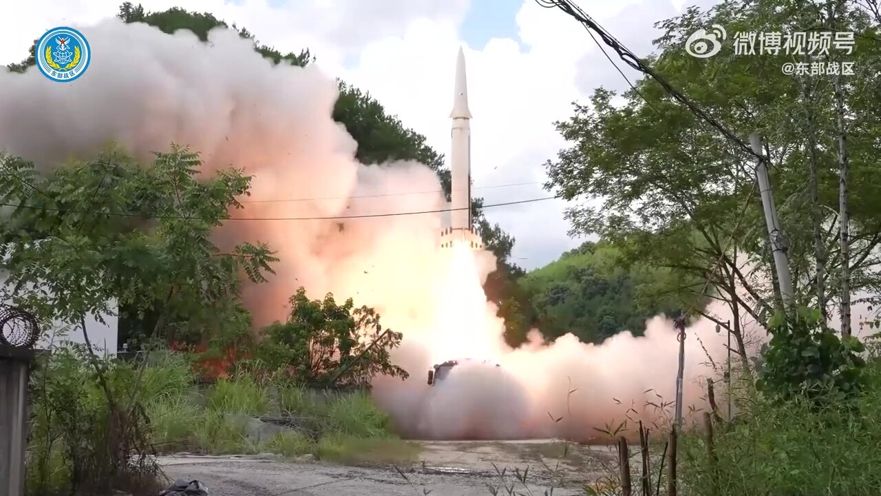 A still from a Chinese military video showing a missile launching amid trees, sending clouds of smoke out below it.