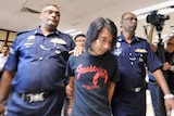 Malaysian police officers escort student activist Adam Adli Halim.