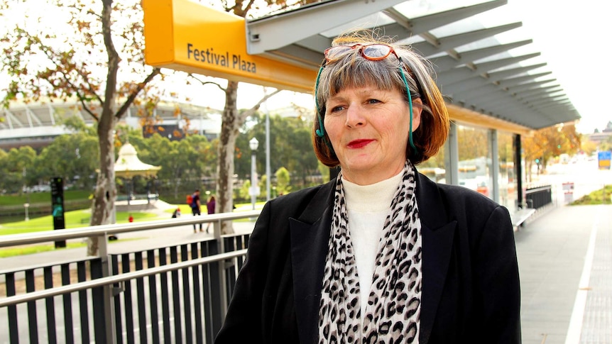 A woman stands at the Festival Plaza bus stop