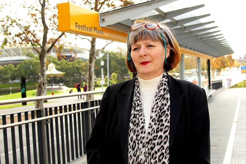 A woman stands at the Festival Plaza bus stop