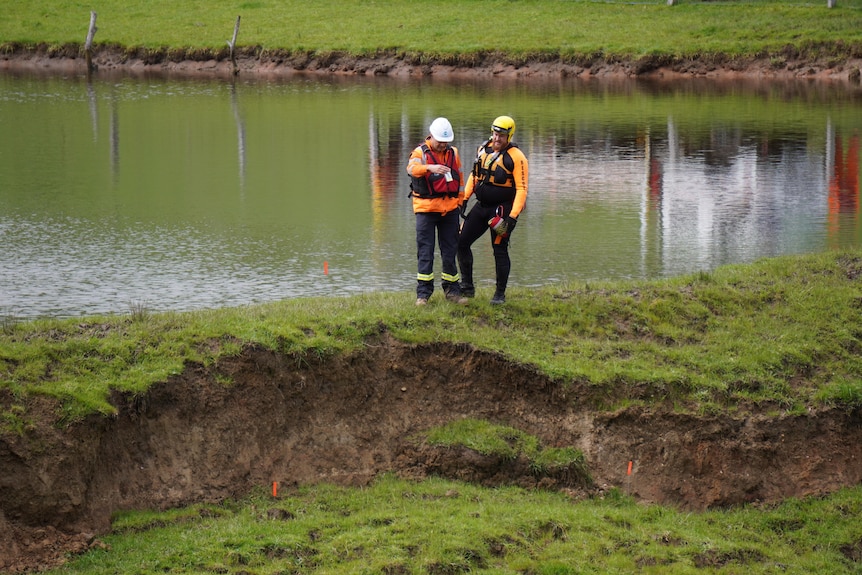 Two SES members next to a dam with mud and grass