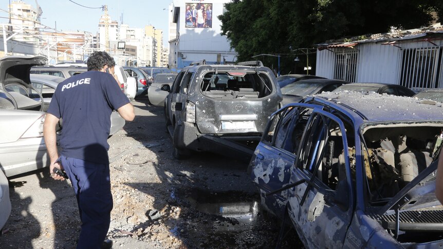 A policeman inspects damaged cars after two rockets hit houses and a caryard in Beirut.