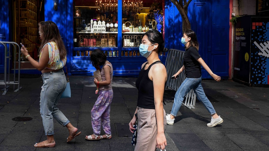 women wearing face masks walking on a street