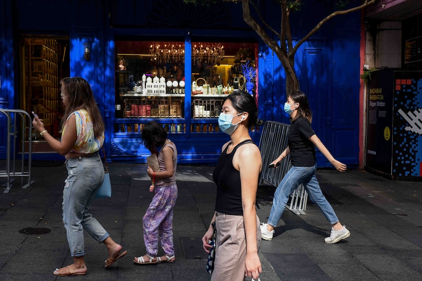 women wearing face masks walking on a street