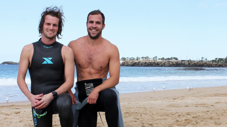 Two surfers kneeling on a beach