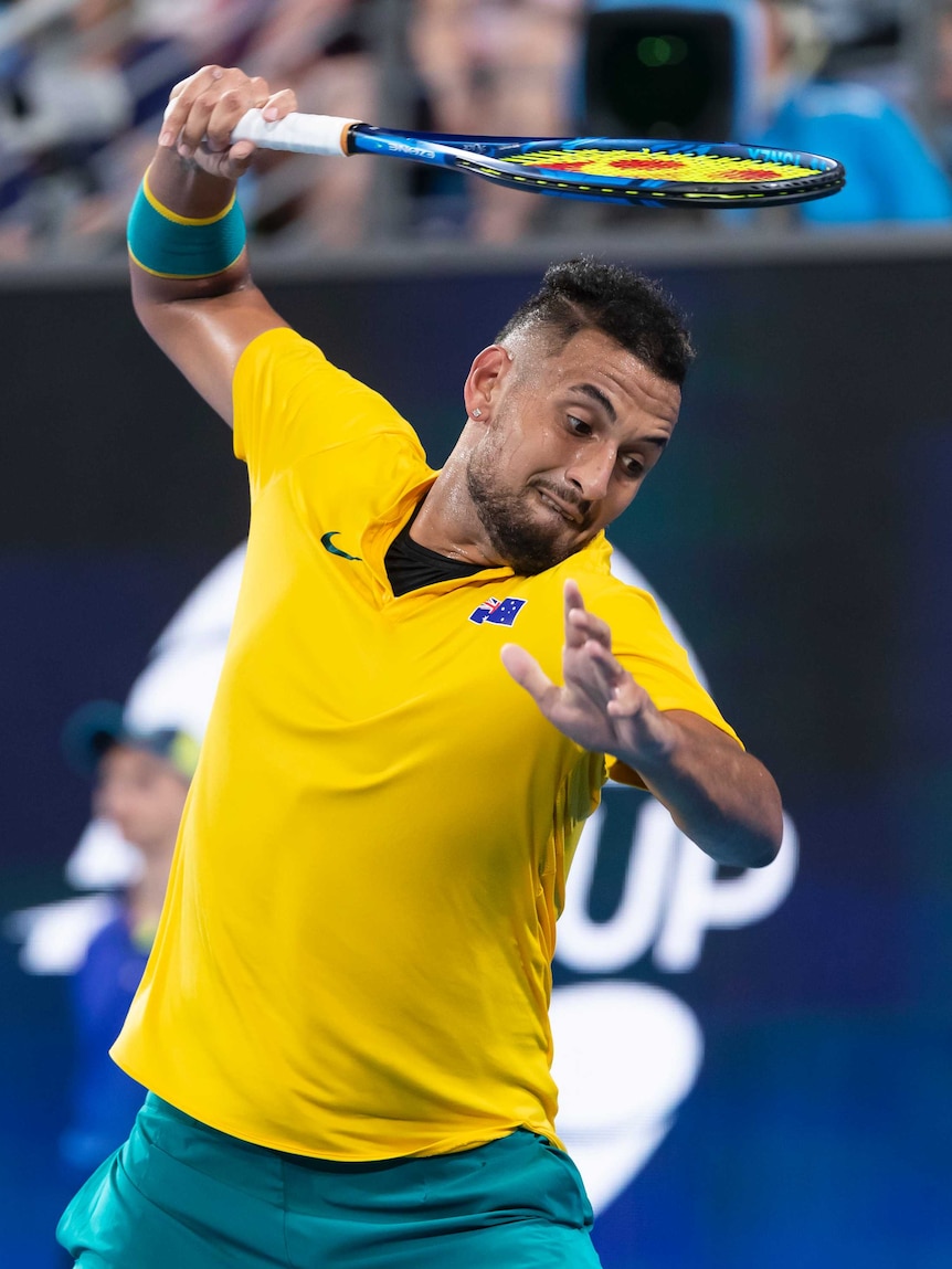 Australian tennis player Nick Kyrgios rises a racket above his head as he prepares to smash it during a match at the ATP Cup.