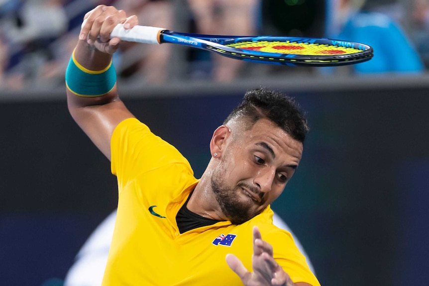 Australian tennis player Nick Kyrgios rises a racket above his head as he prepares to smash it during a match at the ATP Cup.