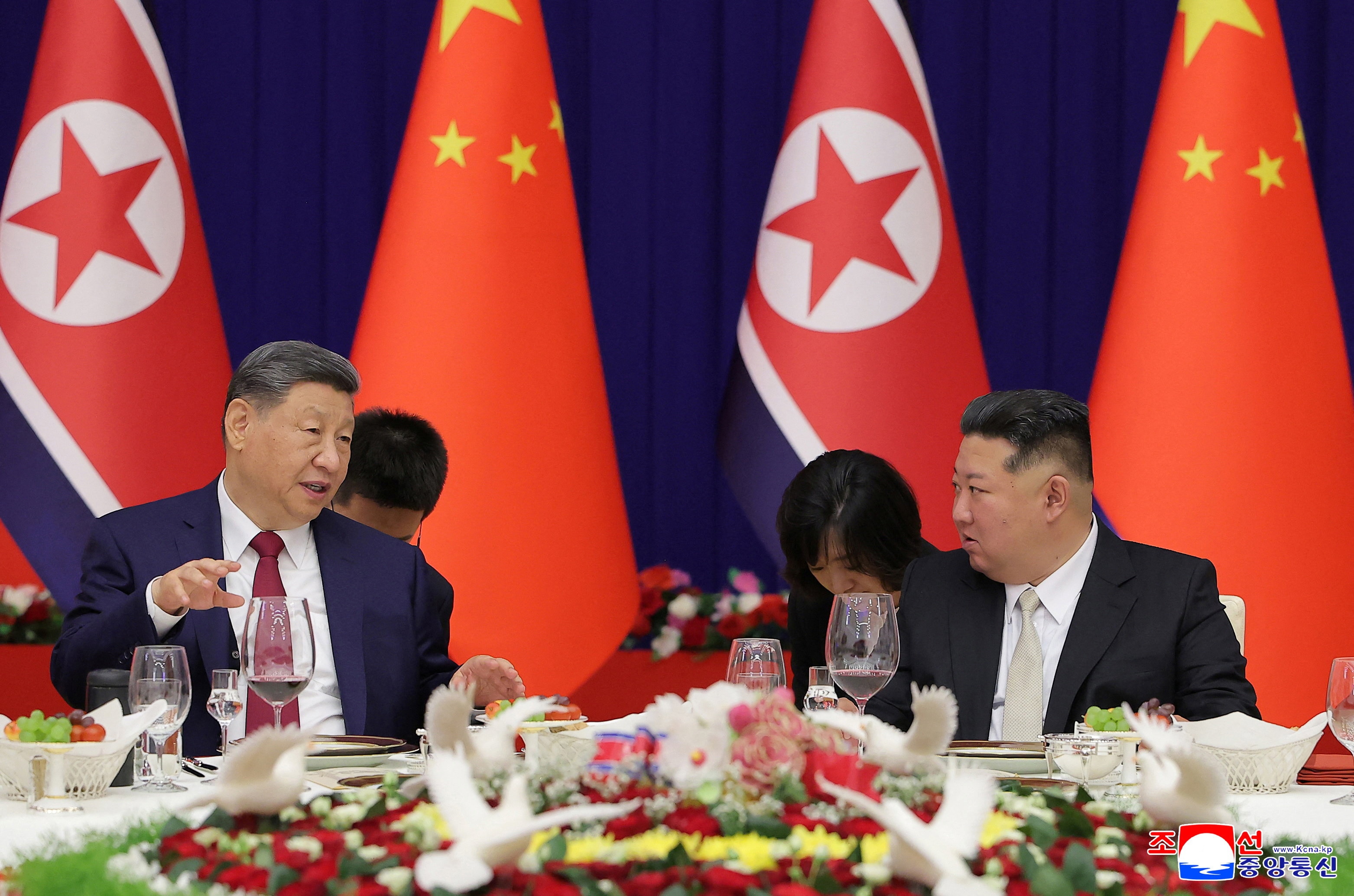 Xi Jinping and Kim Jong Un sit down to a banquet.