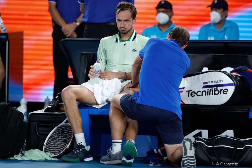 Daniil Medvedev is treated by a trainer as he drinks water during the Australian Open final.