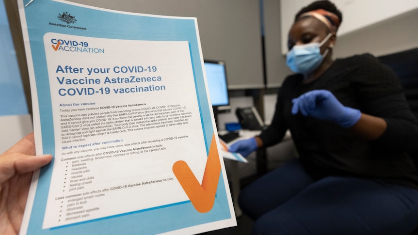 A nurse with an AstraZeneca information sheet in the foreground.