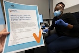 A nurse with an AstraZeneca information sheet in the foreground.