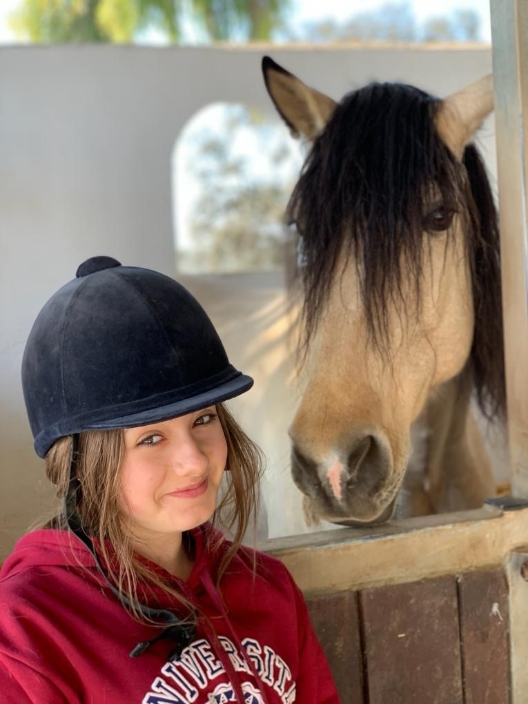 Teenage girl in horse riding hat with horse