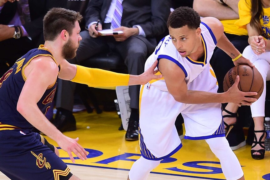 Stephen Curry of the Golden State Warriors looks to pass under pressure from Matthew Dellavedova