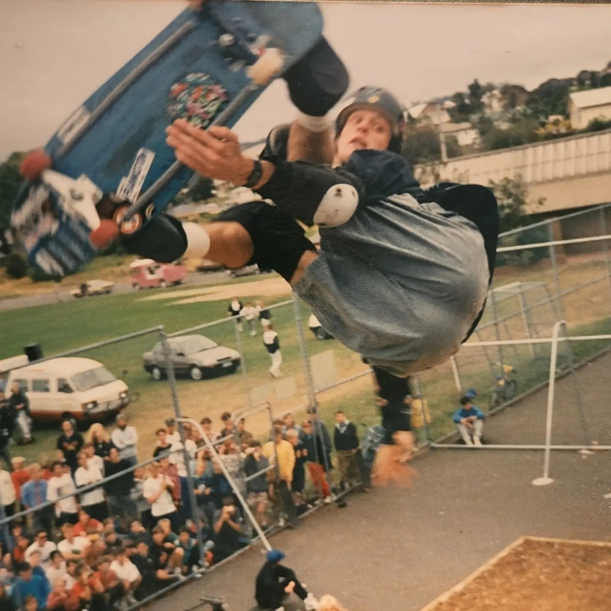 Man on skateboard mid air, wears helmet.