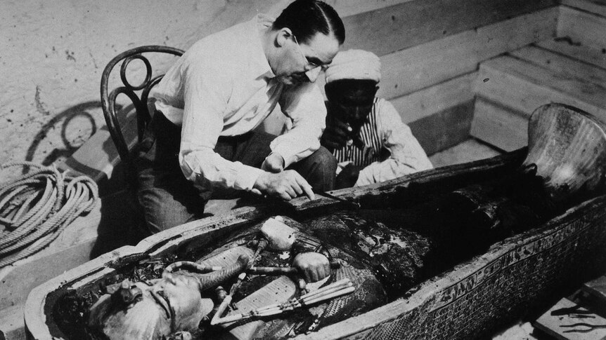 British archaeologist Howard Carter and an Egyptian workman examine the third coffin of Tutankhamun.