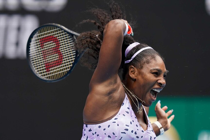 Serena Williams swings at a ball mid play during a tennis match