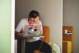 A young man sits in front of a laptop for a story on common misconceptions about ADHD