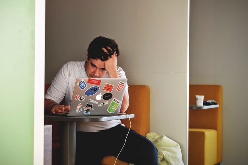 A young man sits in front of a laptop.