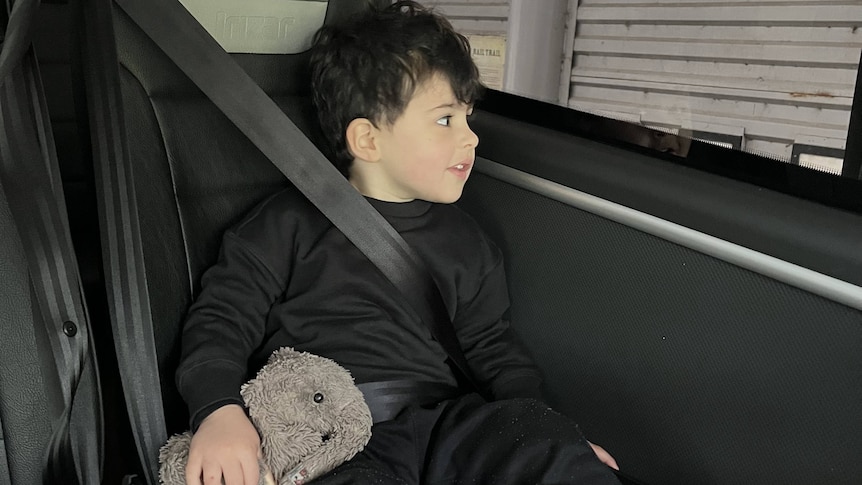 Small boy with plush toy elephant on a bus.