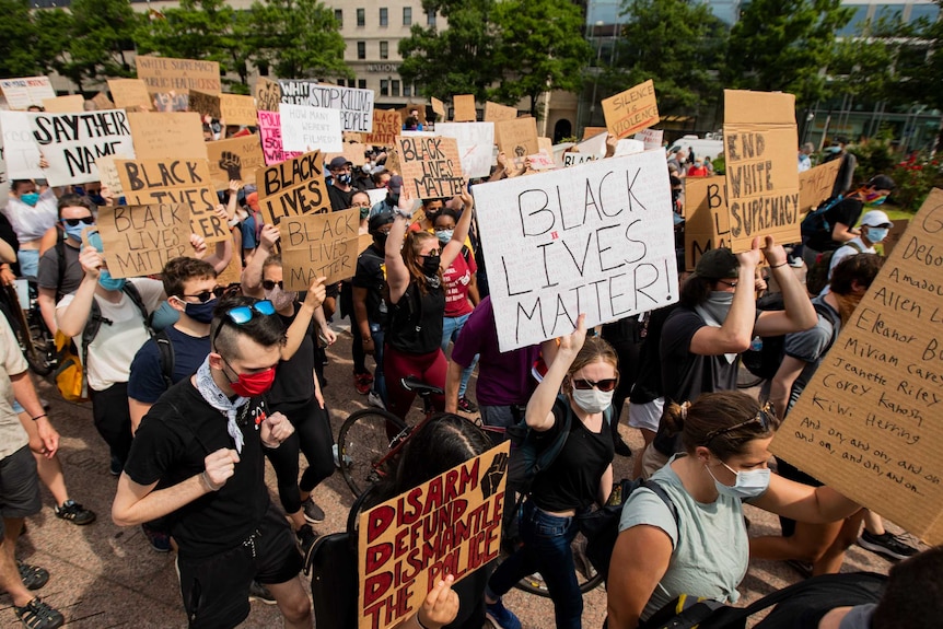 A group of mostly masked protesters holding 'black lives matter' signs