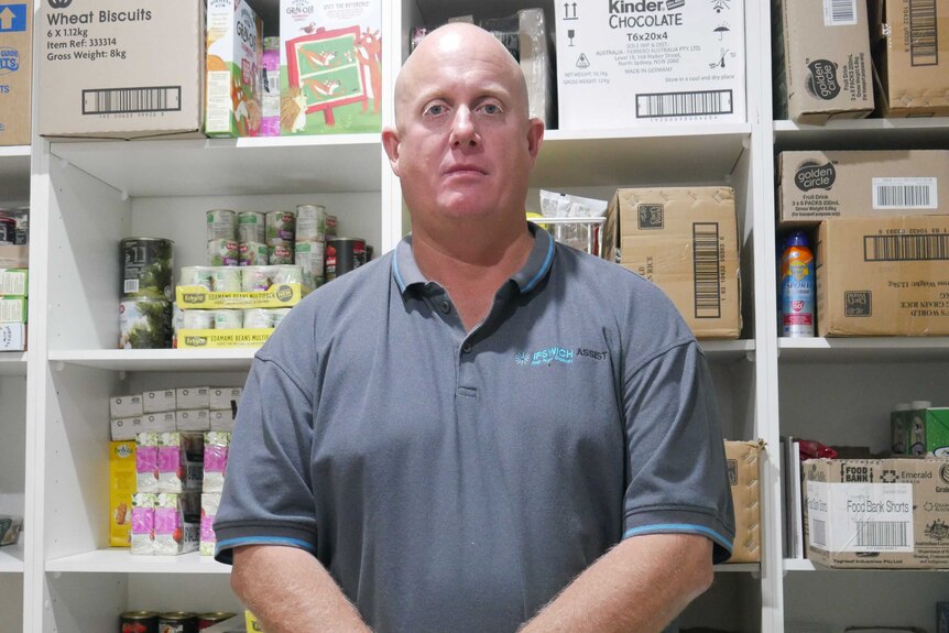 Man stands in front of shelves packed with food