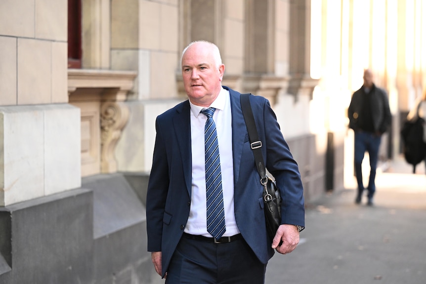 Brett Florence wearing a suit with a blue tie walking into court.