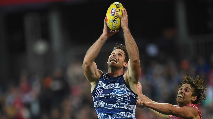 Tom Hawkins looks at the ball as he takes a two-handed mark above his head, with Dane Rampe just behind him.