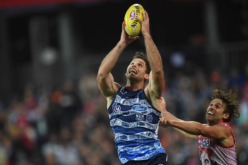 Tom Hawkins looks at the ball as he takes a two-handed mark above his head, with Dane Rampe just behind him.