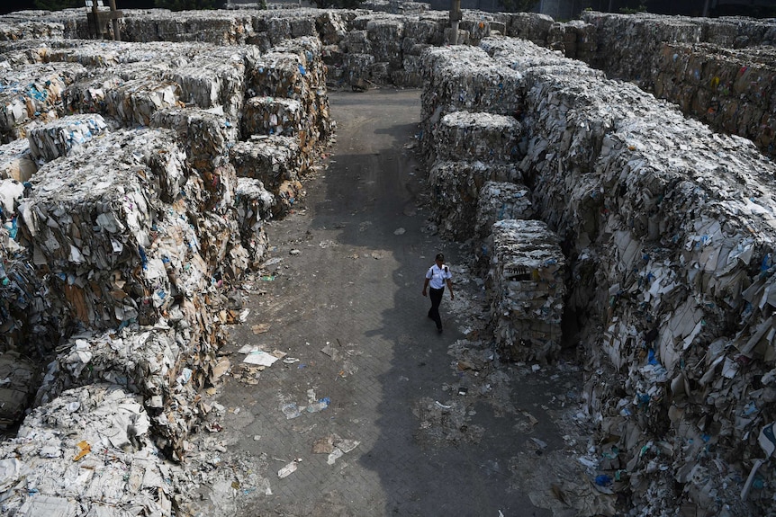 A man walks between huge piles of paper