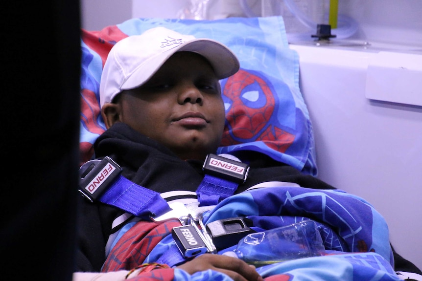 A close-up of 12-year-old Darius Eldouma lying on a stretcher in an ambulance with a Spiderman pillow behind his head.