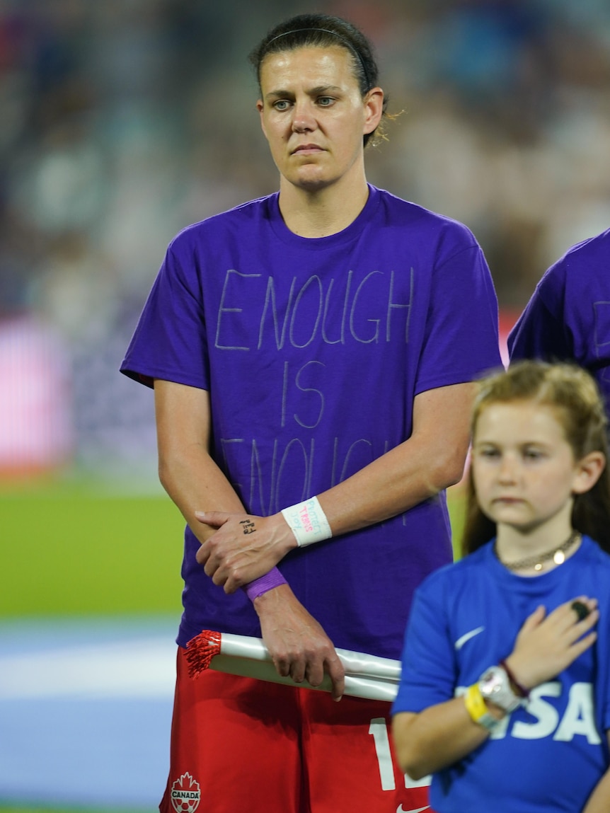A woman soccer player wears a purple t-shirt with a message on it protesting inequality