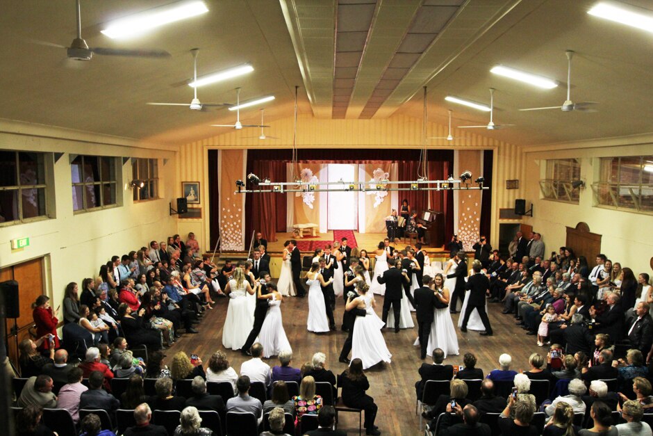 Wide shot of couples dancing, surrounded by spectators.