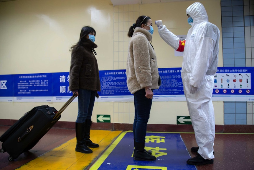 A health worker checks the temperature of women