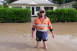 A man in hi-vis stands in floodwaters