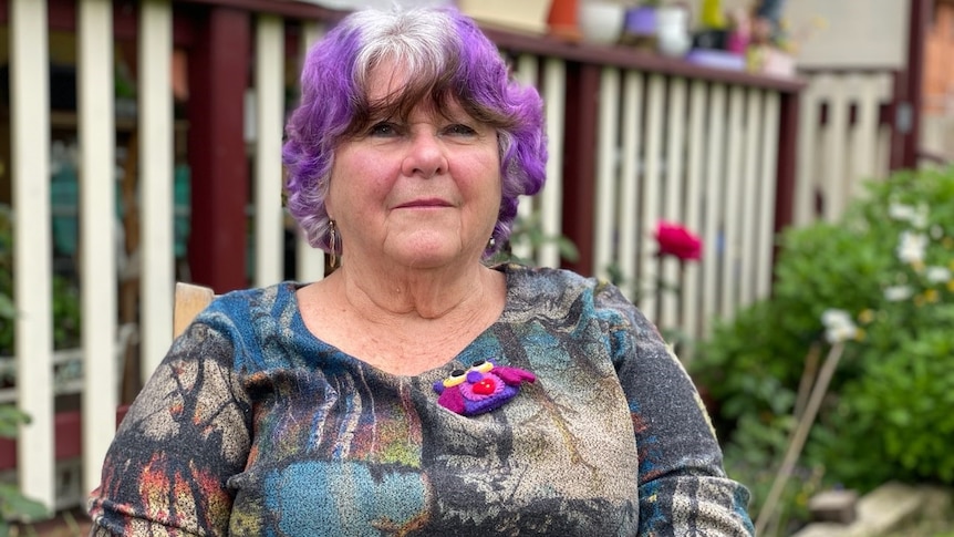 Lady with purple hair looks at the camera.