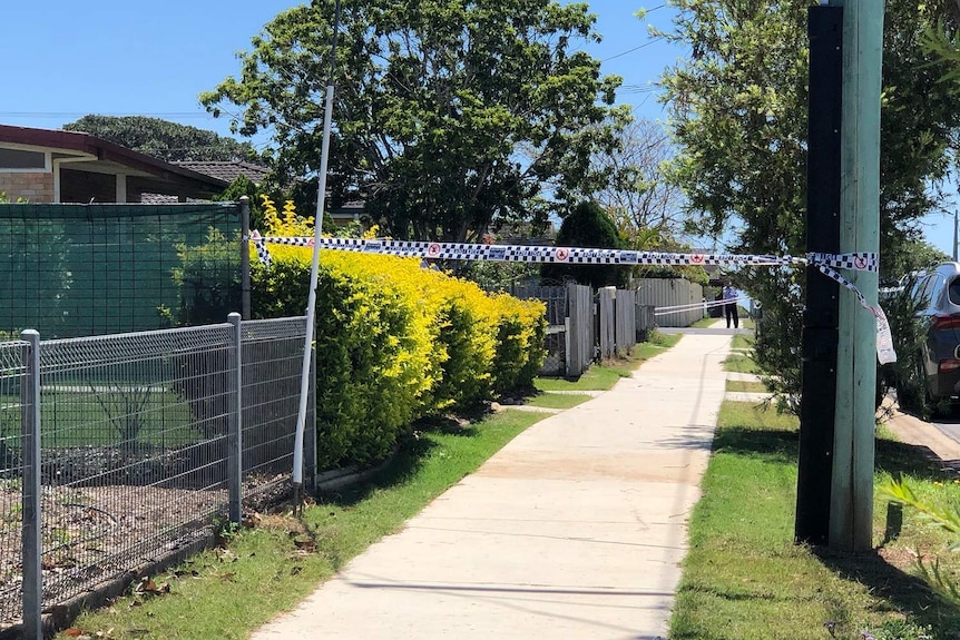 Police tape across a pathway on a suburban street.