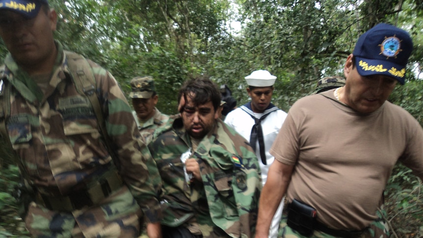 Army officers help a plane crash survivor out of the Amazon