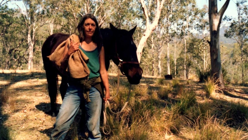 Medium colour archive shot of a woman standing with a horse in a clearing in the Australian bush.