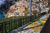 Brightly coloured empty tables on a balcony overlooking the Italian town of Positano