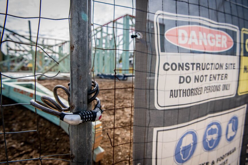 Safety signs outside an empty and padlocked construction site.