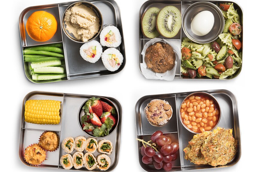 Four lunchboxes with cut up food inside