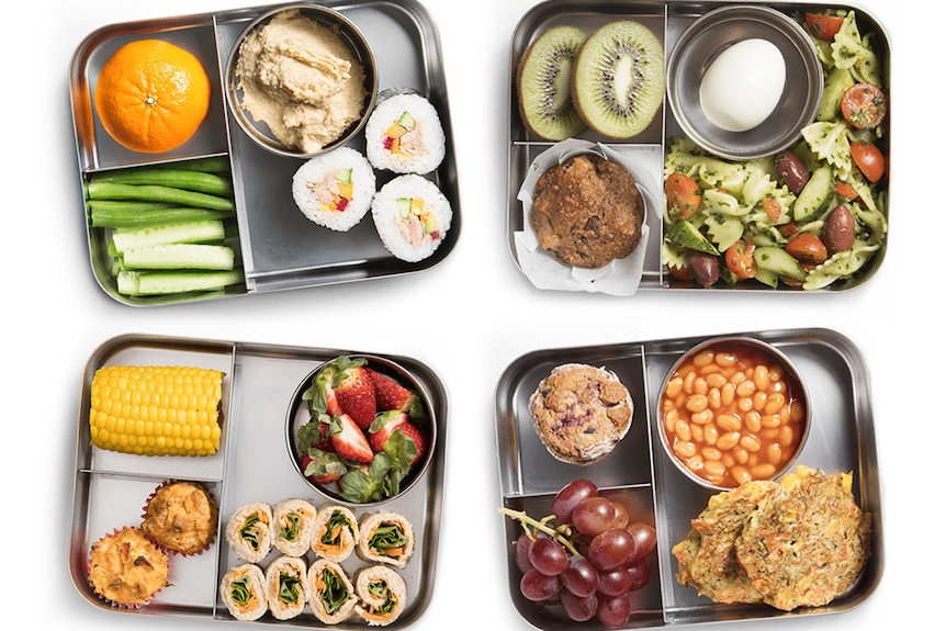 Four lunchboxes with cut up food inside