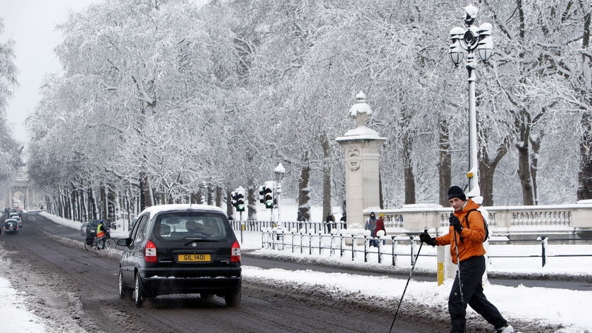 A man makes the most of the 10 centimetre snow coverage in London by skiing to work
