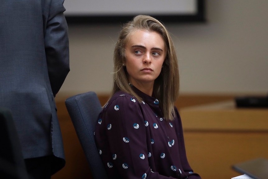 A young woman looks away from the camera as she sits in a court.